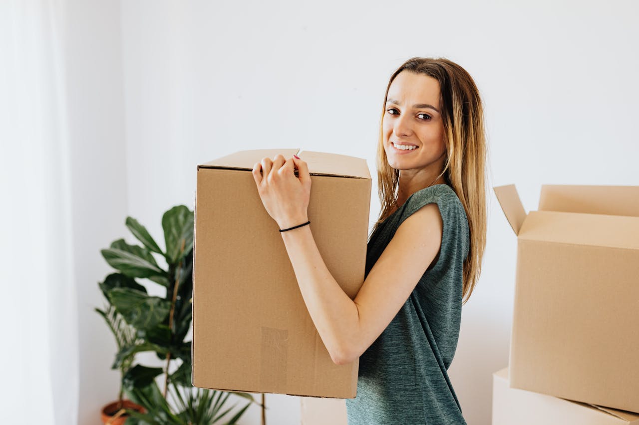 Cheerful woman carrying packed carton box